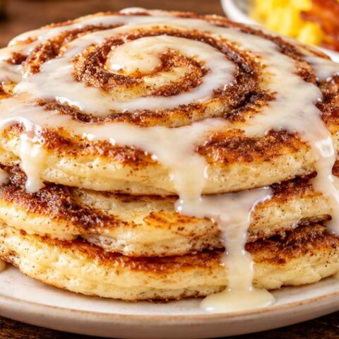 Stack of homemade Cracker Barrel Cinnamon Swirl Pancakes with brown sugar cinnamon filling and cream cheese icing.